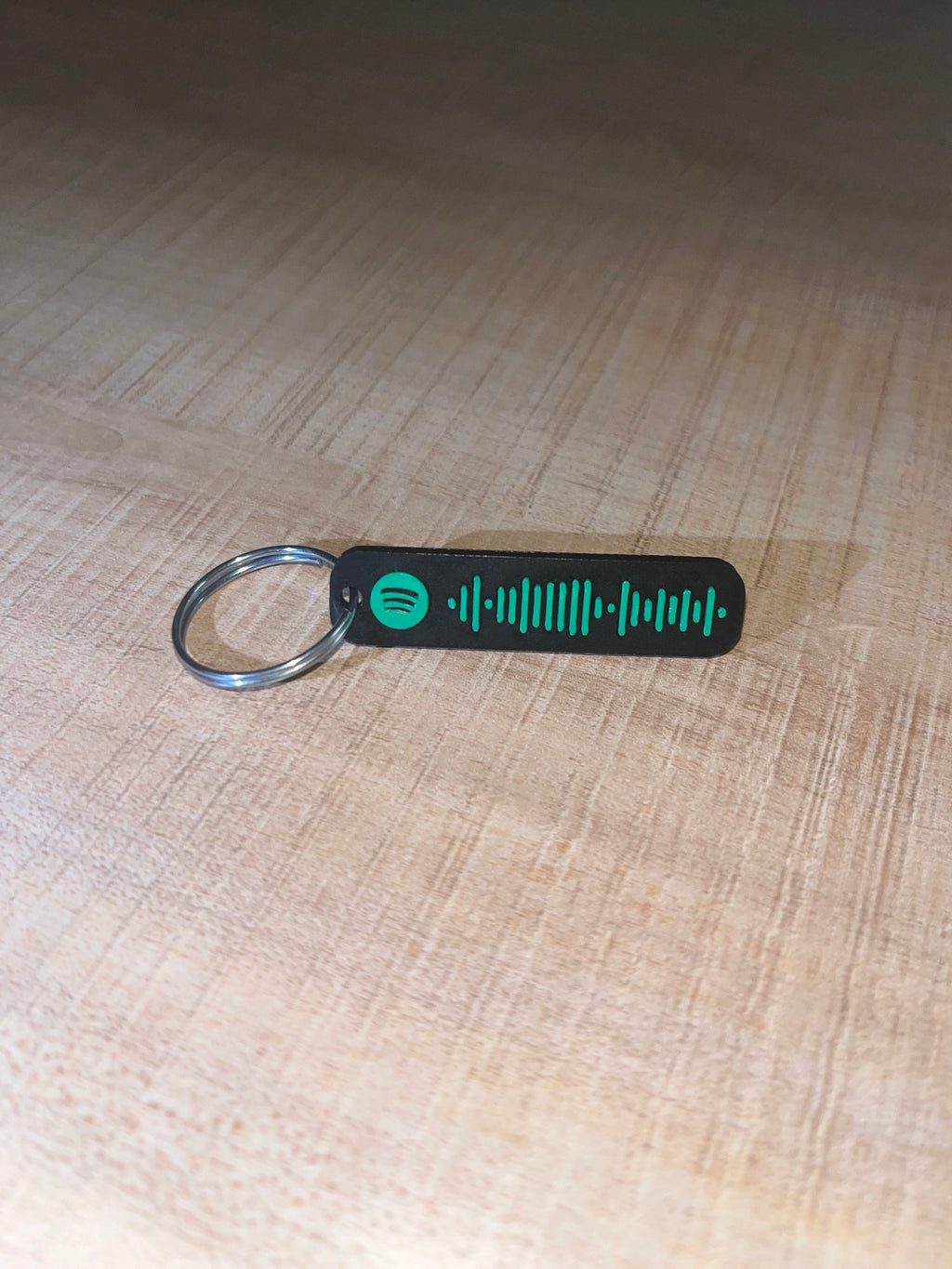 Spotify code keychain with green design on a wooden surface 45 degrees