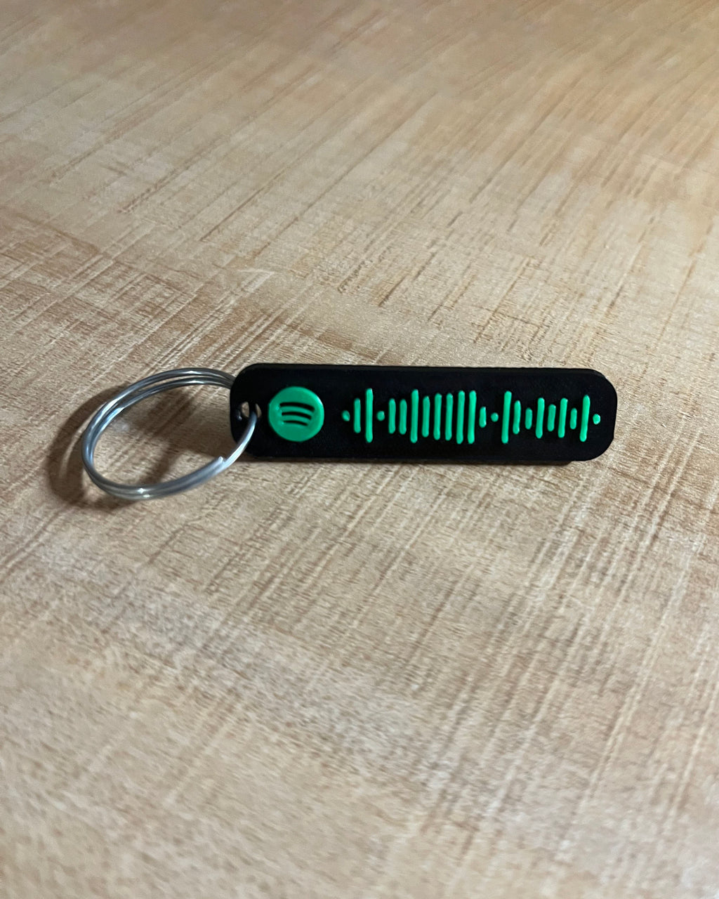 Black keychain with Spotify code on a plastic surface front side